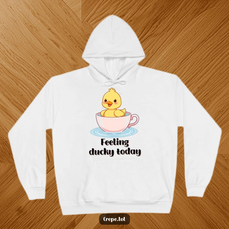 Funny cheerful duckling happily splashing water in a teacup, a cozy and humorous design on a warm hoodie.